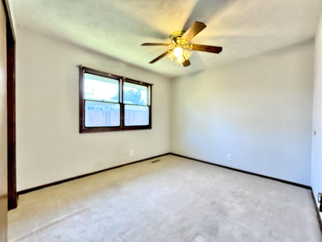 unfurnished room with light colored carpet, baseboards, and ceiling fan