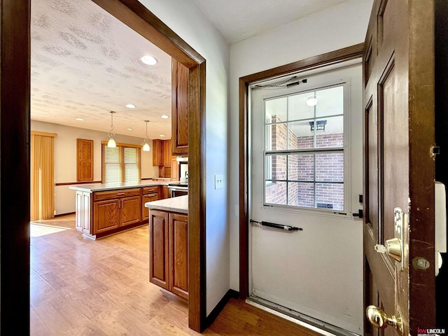 doorway with plenty of natural light, recessed lighting, light wood-style flooring, and baseboards