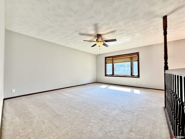 carpeted empty room with baseboards, ceiling fan, and a textured ceiling