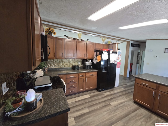 kitchen featuring a textured ceiling, black appliances, and dark countertops