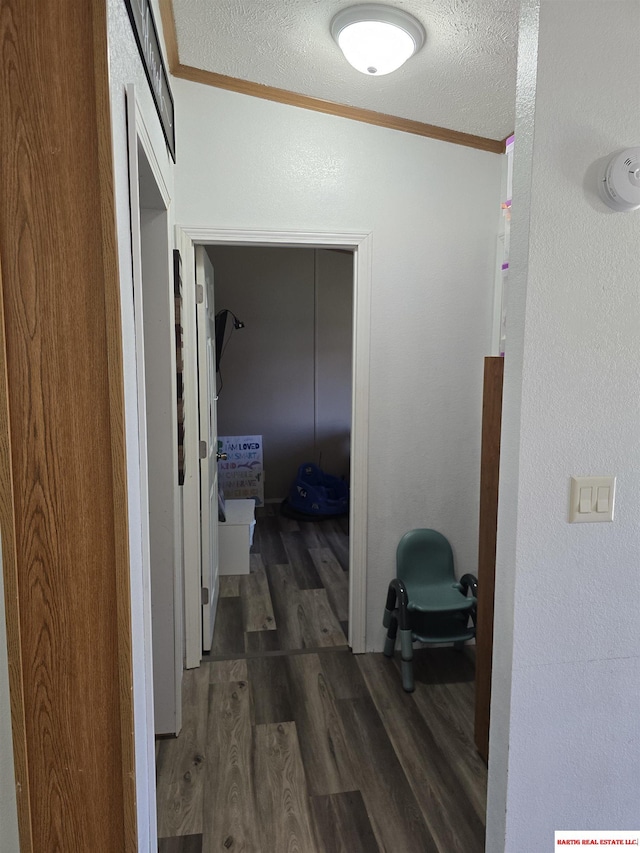 hall featuring crown molding, a textured ceiling, and wood finished floors