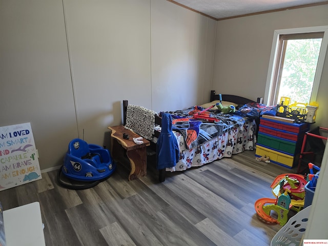 bedroom with crown molding and wood finished floors