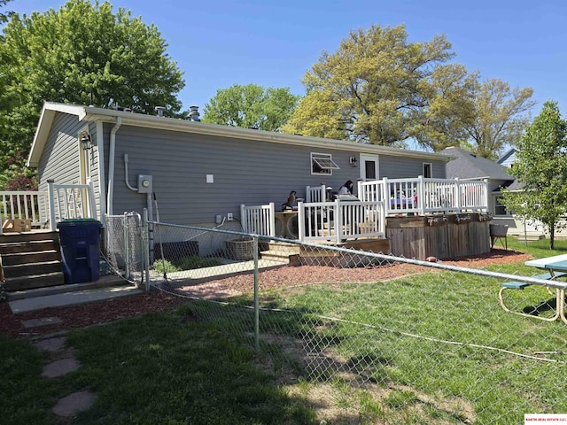 rear view of property featuring a lawn, fence, and a wooden deck