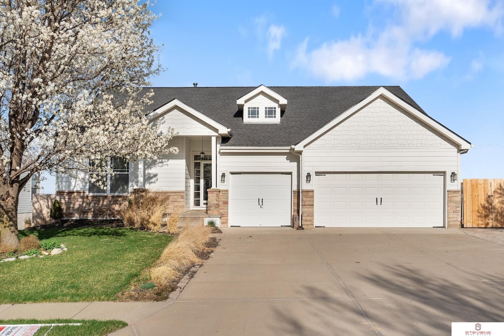 view of front facade with fence, an attached garage, a shingled roof, concrete driveway, and a front lawn