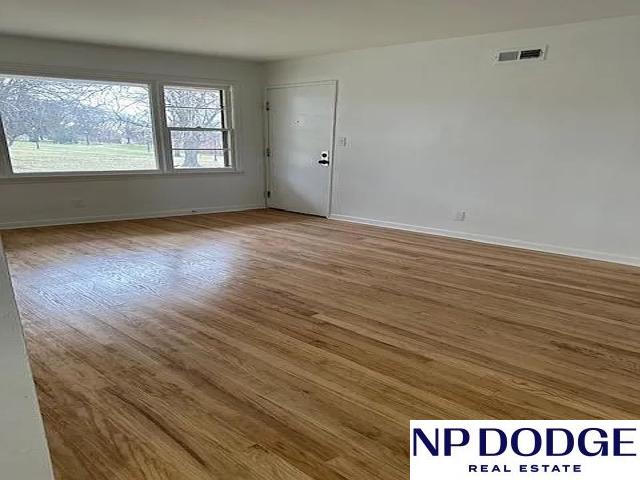 unfurnished room featuring baseboards, visible vents, and wood finished floors