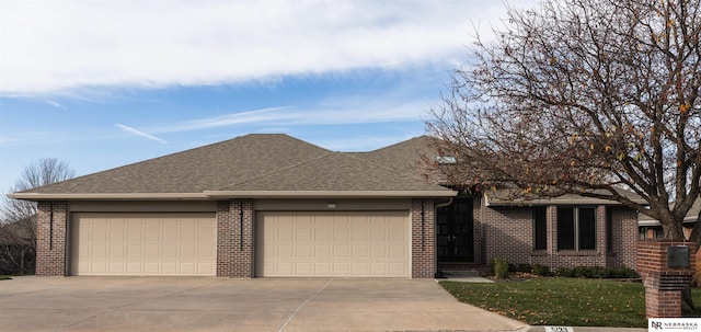 ranch-style house with brick siding, driveway, an attached garage, and roof with shingles
