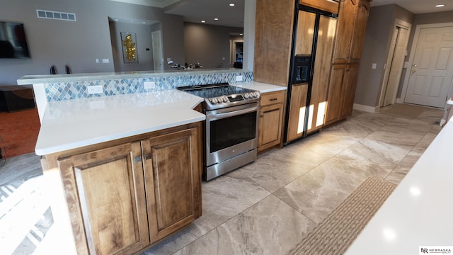 kitchen featuring stainless steel electric range, a peninsula, brown cabinets, light countertops, and recessed lighting