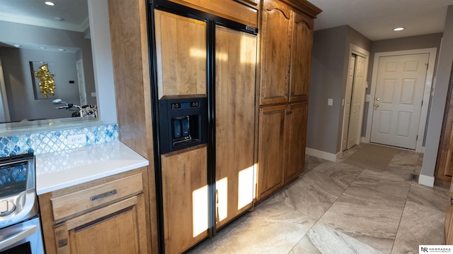 kitchen with paneled refrigerator, light countertops, brown cabinetry, crown molding, and backsplash