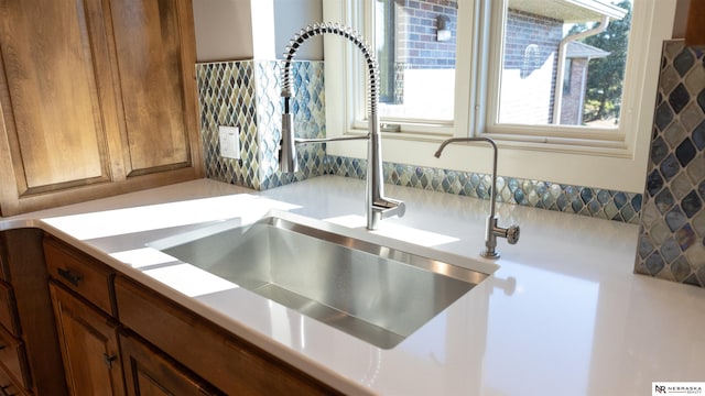 kitchen view of a sink, brown cabinets, and light countertops