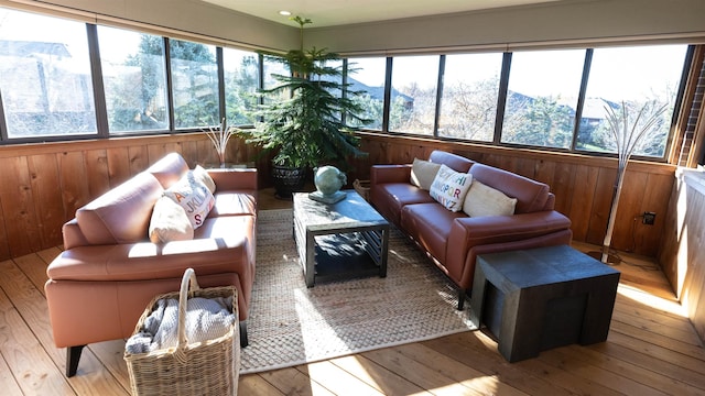 sunroom featuring wood walls, plenty of natural light, wood-type flooring, and a deck