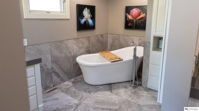 full bath with tile walls, a soaking tub, and wainscoting