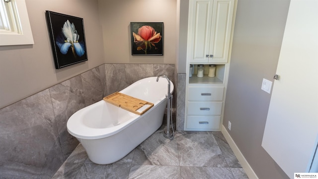 bathroom featuring tile walls, a soaking tub, and a wainscoted wall