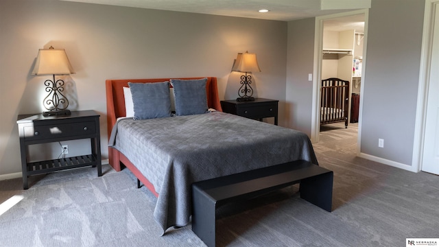 bedroom with carpet floors, baseboards, and a walk in closet
