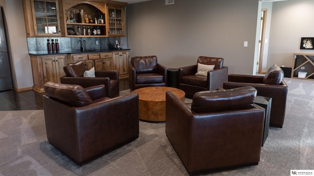 living room featuring bar with sink and dark carpet