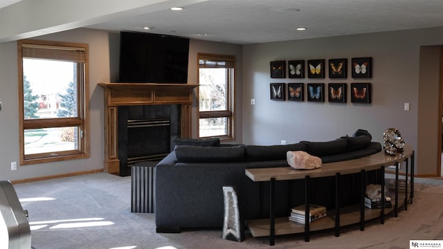 carpeted living area with plenty of natural light, a premium fireplace, baseboards, and recessed lighting