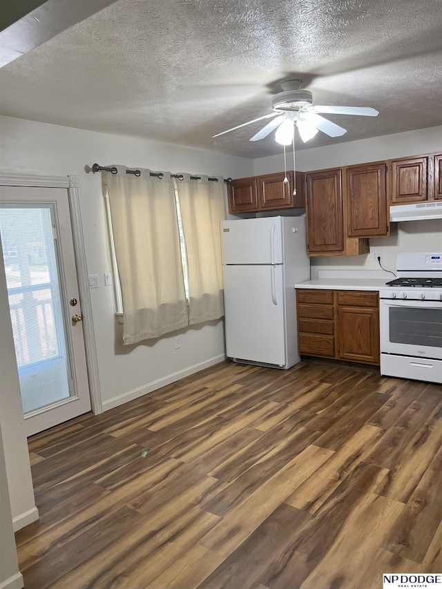 kitchen featuring a textured ceiling, under cabinet range hood, dark wood-style flooring, white appliances, and light countertops