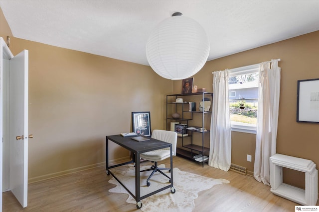 home office with light wood-style flooring and baseboards