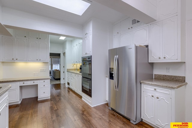 1638 N Nye Ave, Fremont, NE 68025 - kitchen with dobule oven black, stainless steel fridge with ice dispenser, white cabinets, and a skylight