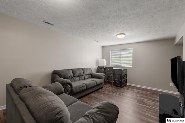 living area featuring a textured ceiling, visible vents, wood finished floors, and baseboards