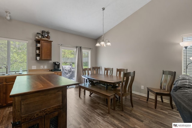 dining room with dark wood-style flooring, a notable chandelier, a healthy amount of sunlight, and vaulted ceiling