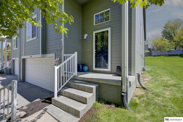 doorway to property featuring concrete driveway, a yard, fence, and a garage