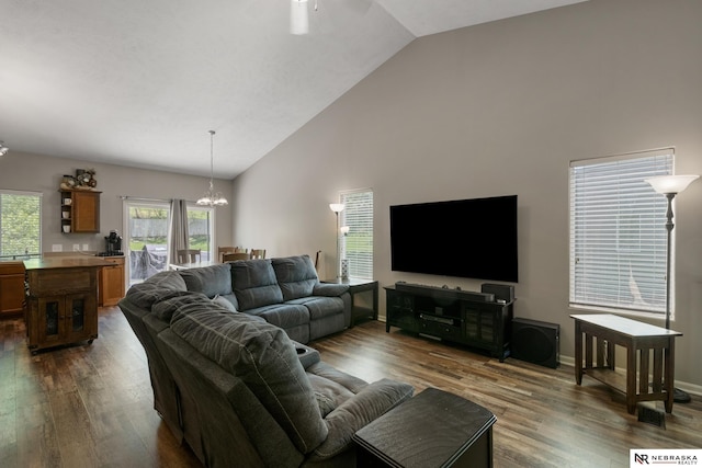living area featuring dark wood-style flooring, ceiling fan with notable chandelier, baseboards, and high vaulted ceiling