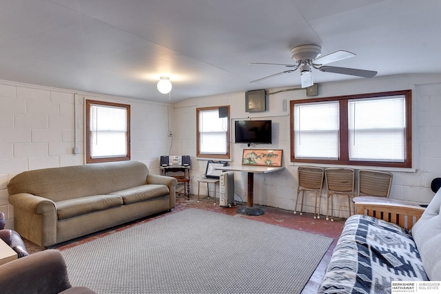 living area featuring ceiling fan and concrete block wall
