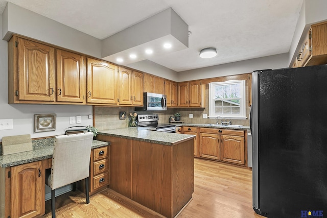 kitchen with light wood-style flooring, brown cabinetry, a peninsula, decorative backsplash, and stainless steel appliances