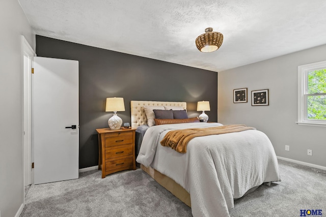carpeted bedroom featuring a textured ceiling and baseboards