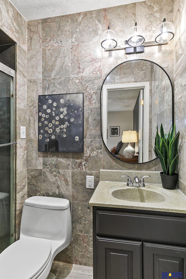 bathroom with tile walls, a textured ceiling, toilet, and vanity