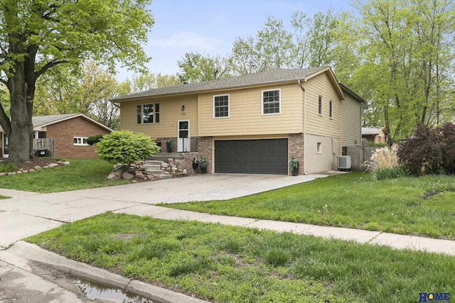 bi-level home featuring an attached garage, brick siding, concrete driveway, a front lawn, and cooling unit