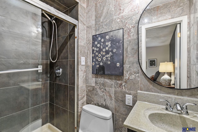 bathroom featuring tile walls, toilet, a shower stall, and vanity