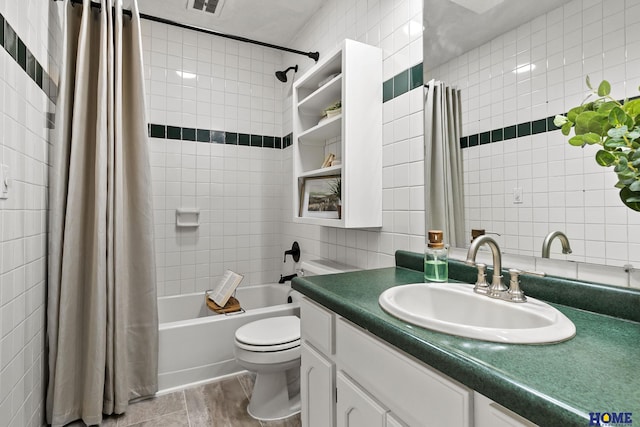 full bath featuring tile walls, toilet, visible vents, vanity, and shower / bathtub combination with curtain