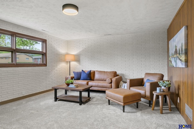 living area with brick wall, a textured ceiling, and carpet