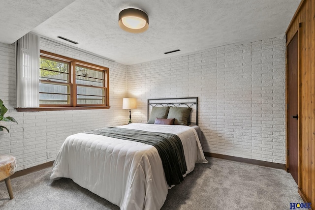 carpeted bedroom featuring baseboards, brick wall, visible vents, and a textured ceiling