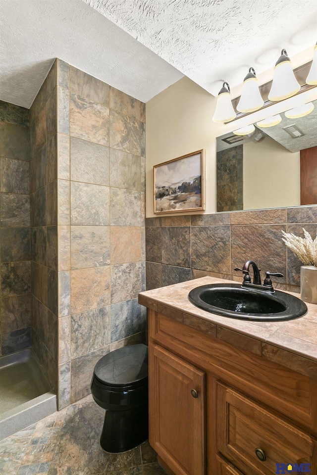 full bath with toilet, tile walls, vanity, a textured ceiling, and a tile shower
