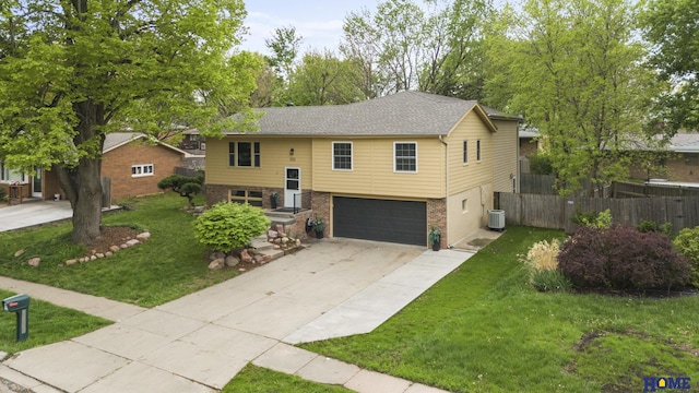 bi-level home with brick siding, fence, a garage, concrete driveway, and a front yard