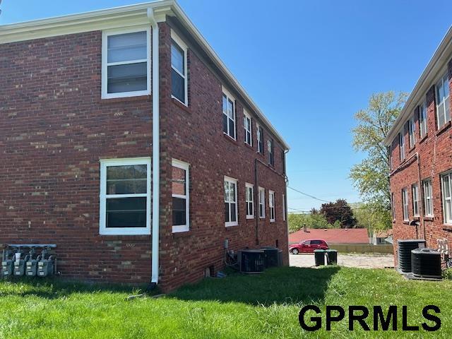 view of home's exterior featuring a yard, brick siding, and central AC