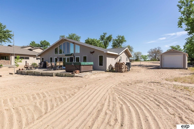 S-1129 Platte Shore Dr, Fremont, NE 68025 - back of house featuring a hot tub, dirt driveway, a garage, and an outdoor structure