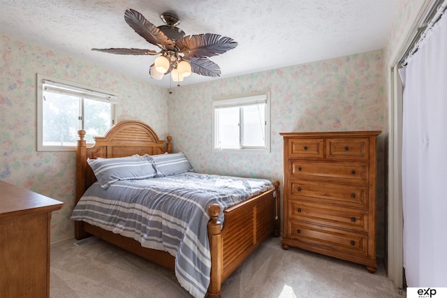 S-1129 Platte Shore Dr, Fremont, NE 68025 - bedroom featuring wallpapered walls, light colored carpet, a ceiling fan, and a textured ceiling