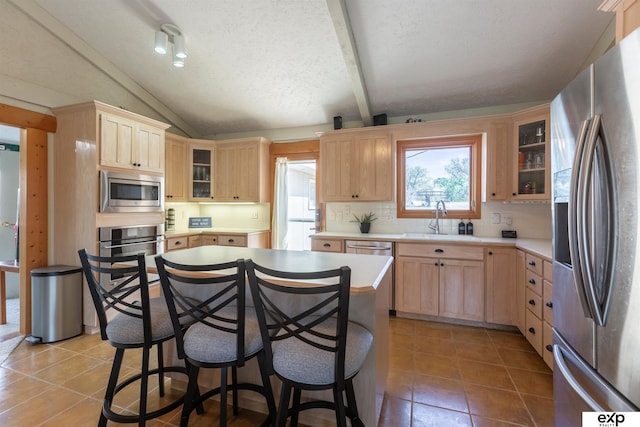 S-1129 Platte Shore Dr, Fremont, NE 68025 - kitchen featuring stainless steel appliances, light brown cabinetry, a sink, vaulted ceiling, and light tile patterned flooring