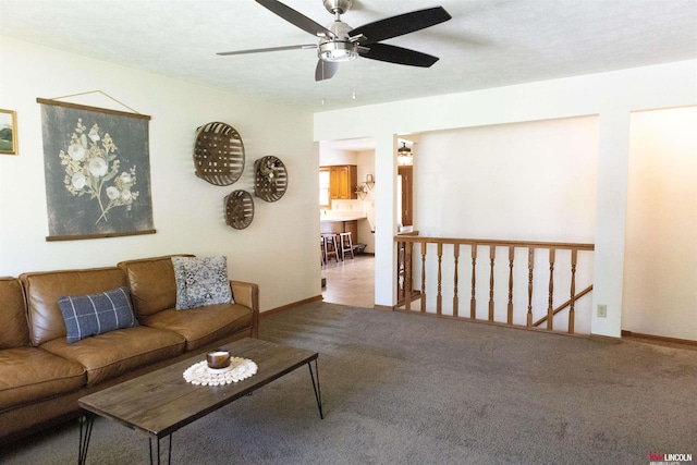 carpeted living area with baseboards and ceiling fan