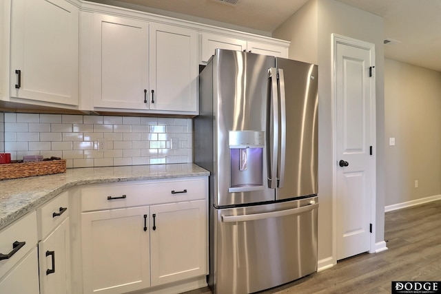 kitchen featuring baseboards, white cabinetry, stainless steel fridge, decorative backsplash, and wood finished floors