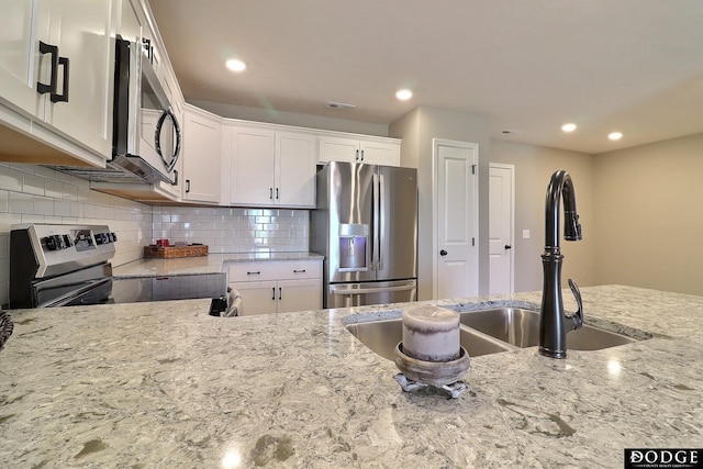 kitchen with light stone counters, visible vents, appliances with stainless steel finishes, and a sink