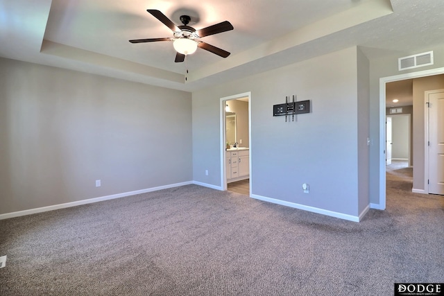 unfurnished bedroom with a raised ceiling, carpet flooring, baseboards, and visible vents