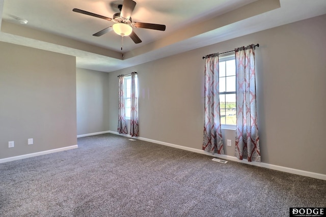 empty room with plenty of natural light, baseboards, a raised ceiling, and ceiling fan
