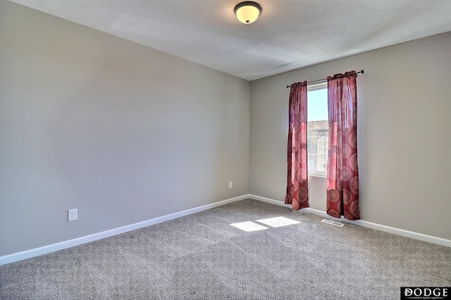 empty room featuring carpet flooring, visible vents, and baseboards