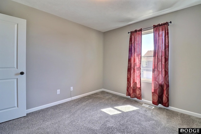 spare room featuring carpet, visible vents, and baseboards