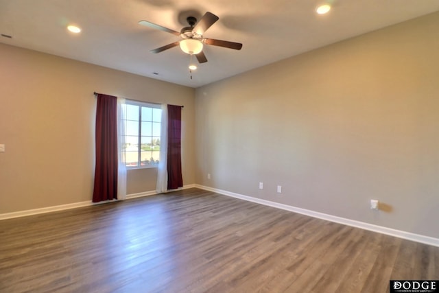 spare room featuring baseboards, dark wood finished floors, and ceiling fan