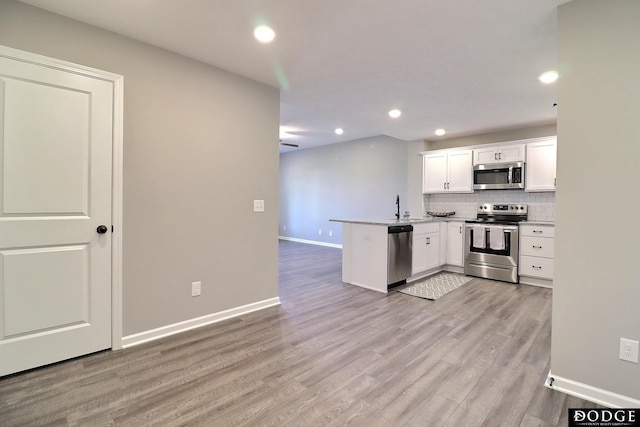 kitchen with recessed lighting, white cabinetry, a peninsula, decorative backsplash, and appliances with stainless steel finishes